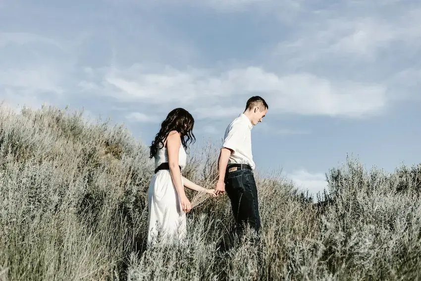 Couple walks across a grassy field