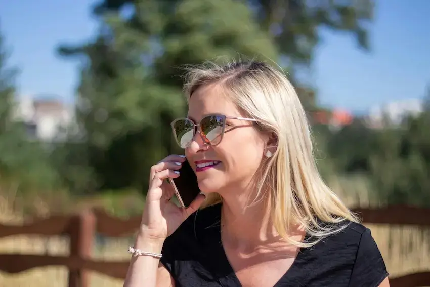 Woman in black tank top wearing black framed eyeglasses talking on the phone